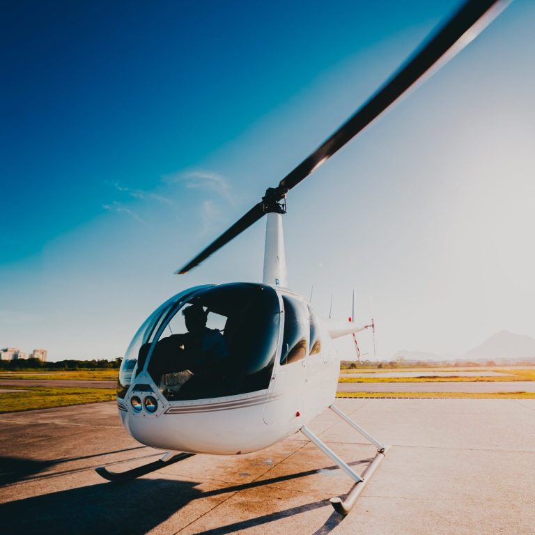 Photo d'un hélicoptère R44 blanc vue de trois quart face avec un grand ciel bleu