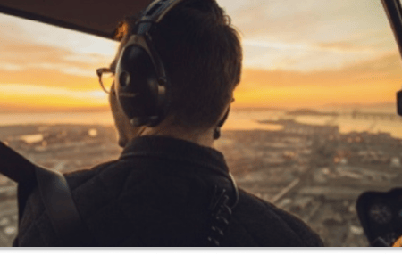 Homme dans un hélicoptère en vol. Coucher de soleil au dessus d'une grande ville